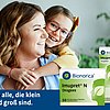 Person hält ein Kind im Arm, beide Gesichter sind unscharf dargestellt. Im Vordergrund stehen zwei Packungen des pflanzlichen Erkältungsmittels Imupret® N von Bionorica: Dragees und Tropfen. Text im Bild: „Für alle, die klein und groß sind.“
